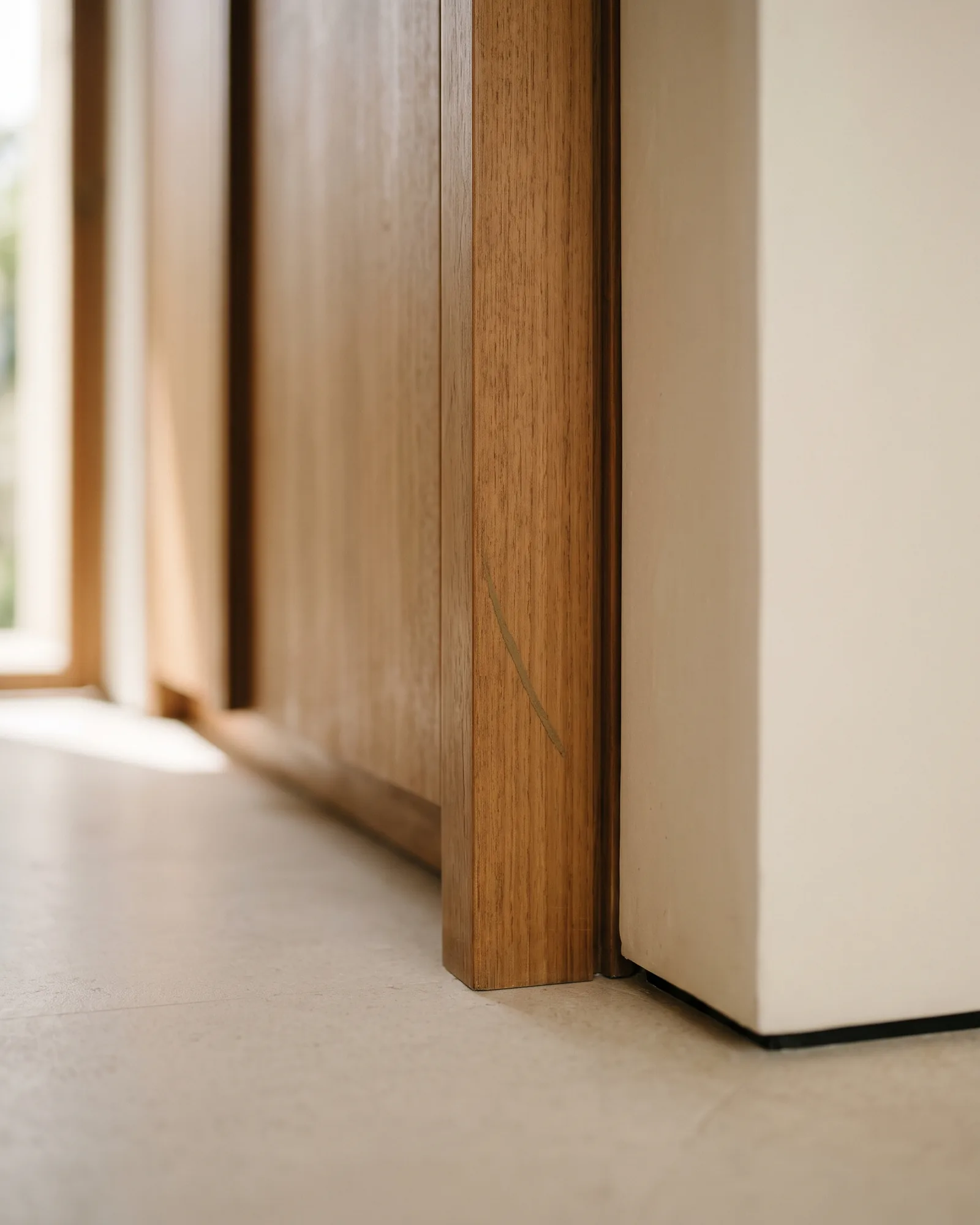 A single faint line of dried earth on the teak end stile at the base of an otherwise clean built-in wardrobe.