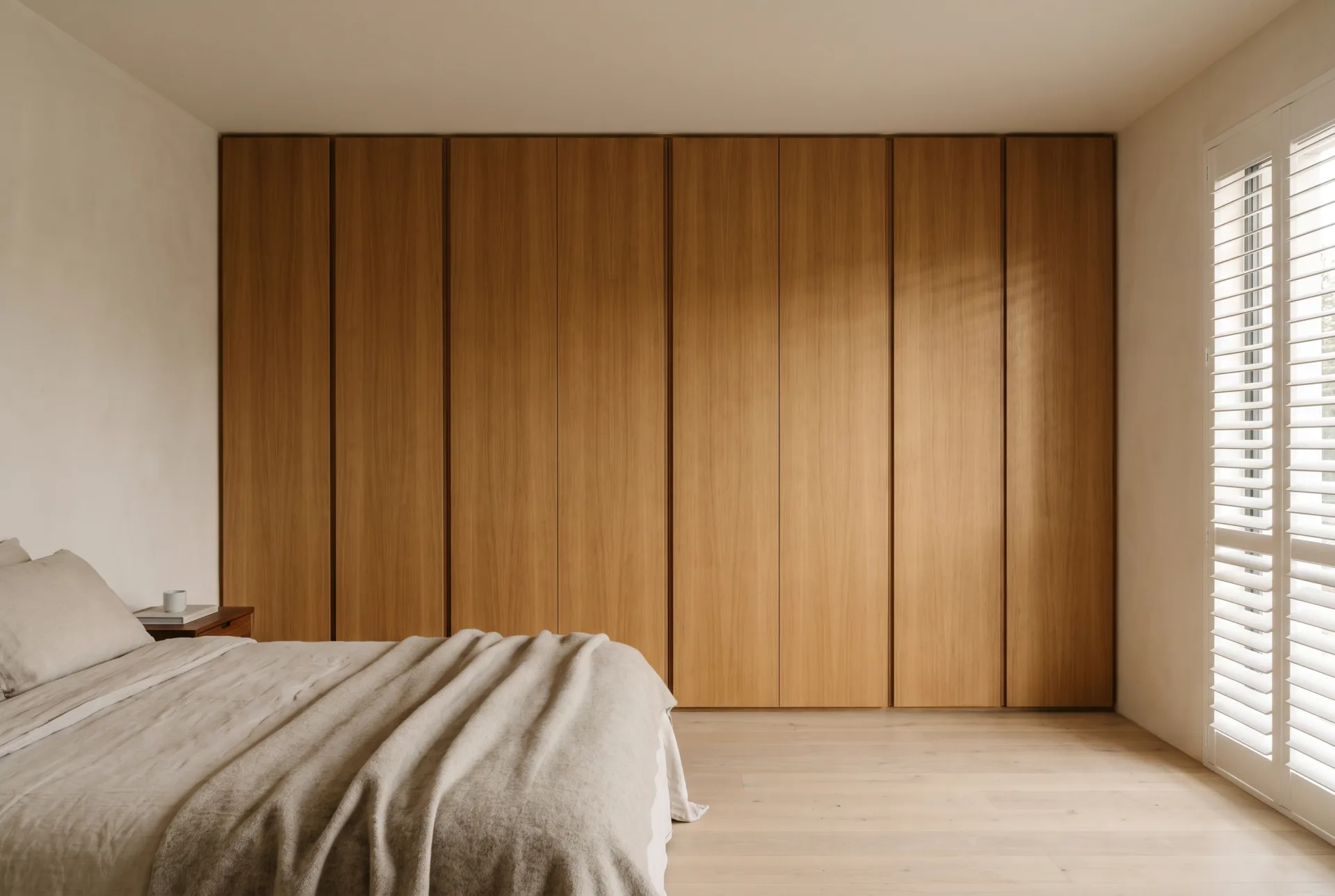 Floor-to-ceiling built-in wardrobe concept with grain-matched oak doors in a bright bedroom