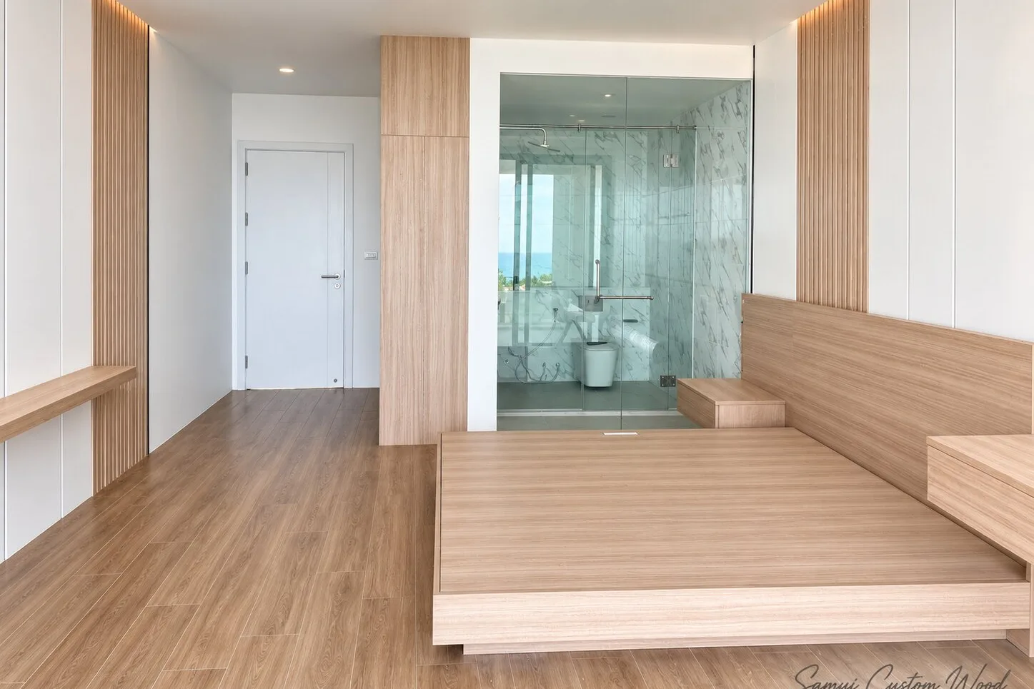 Bedroom suite with platform bed, slat wall panels and a glass bathroom with sea view