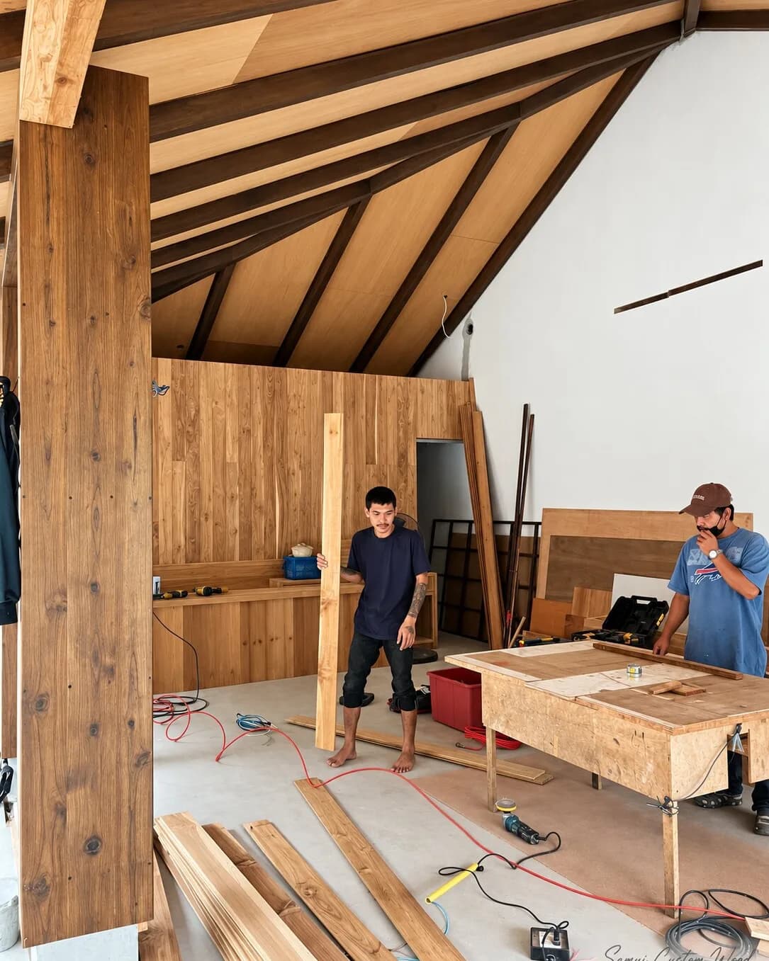 Carpenters fitting timber wall panelling under a pitched panel ceiling