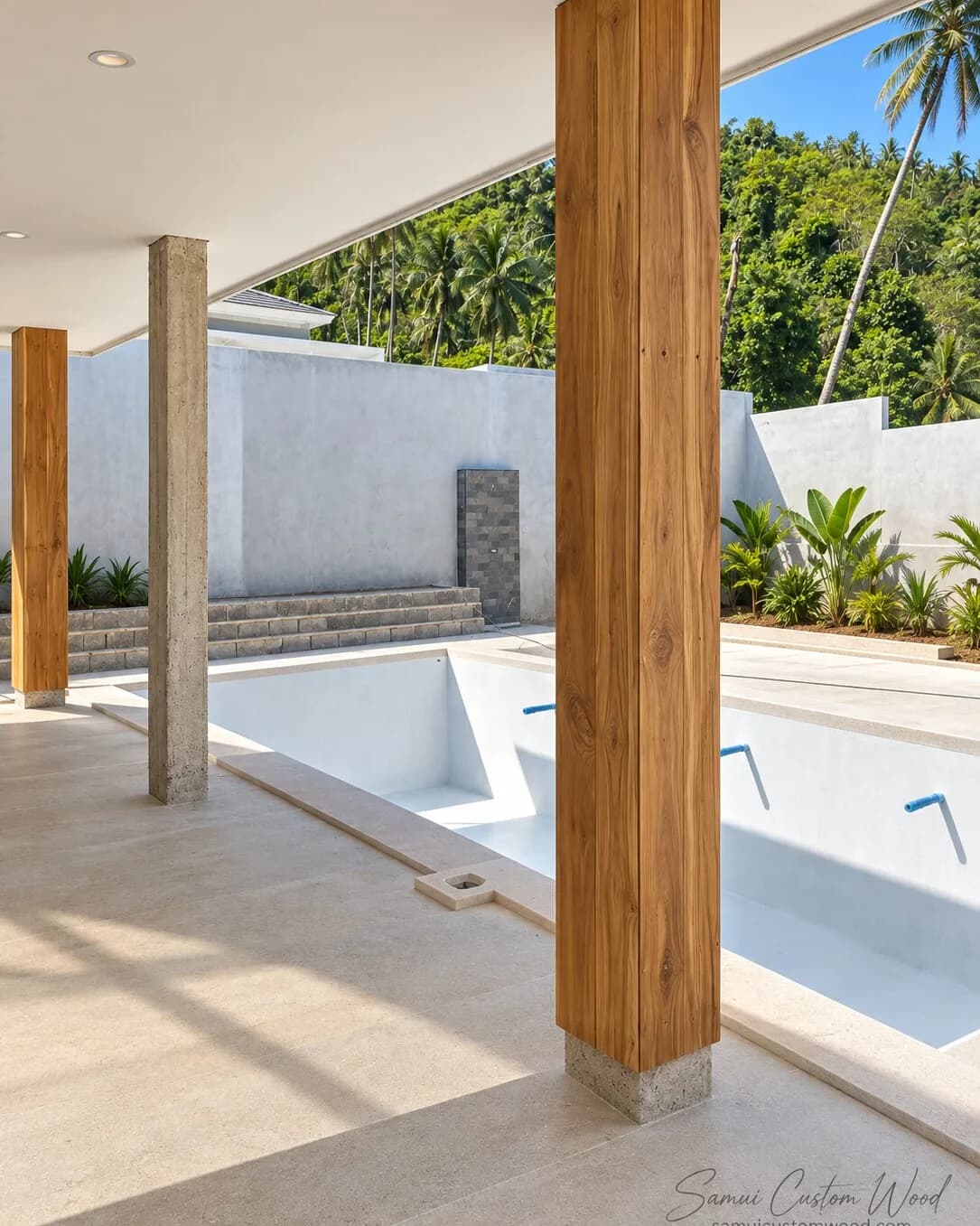 Plank-clad teak column beside an empty pool with jungle hills behind