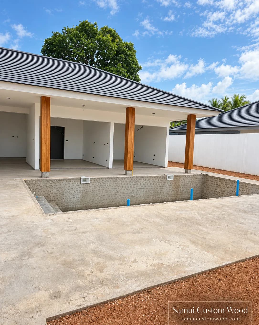 Row of teak-clad columns along a covered villa terrace, seen from across an unfinished pool