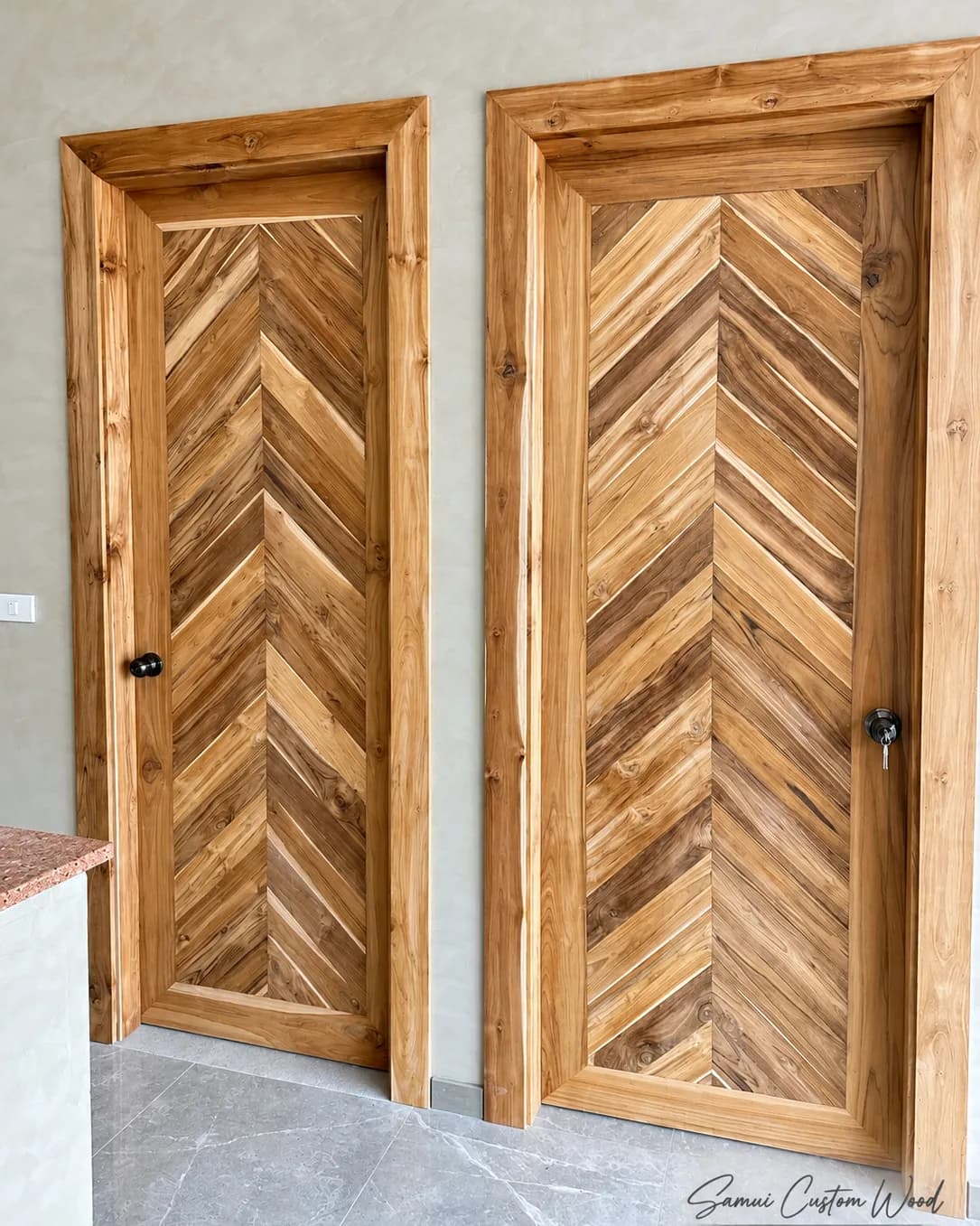 Two chevron-pattern teak doors in solid frames along a plastered wall