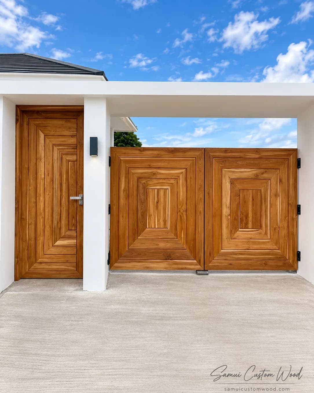 Teak driveway gates beside a matching layered pedestrian door at a villa entrance