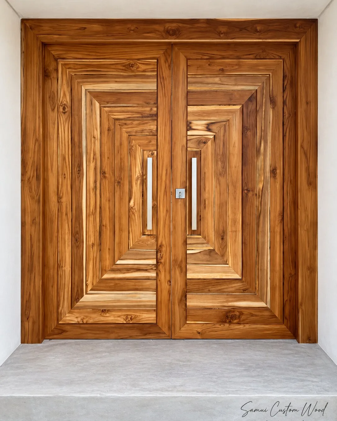 Double entrance doors in layered concentric teak panels with steel pulls