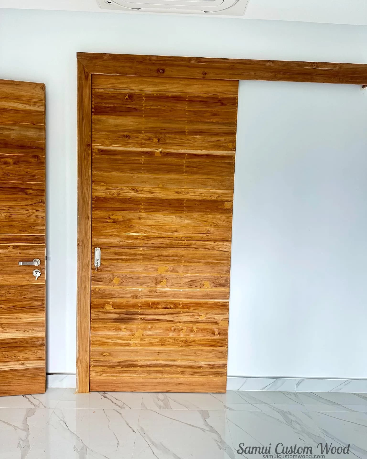 Wide teak sliding leaf on an exposed track beside a hinged plank door