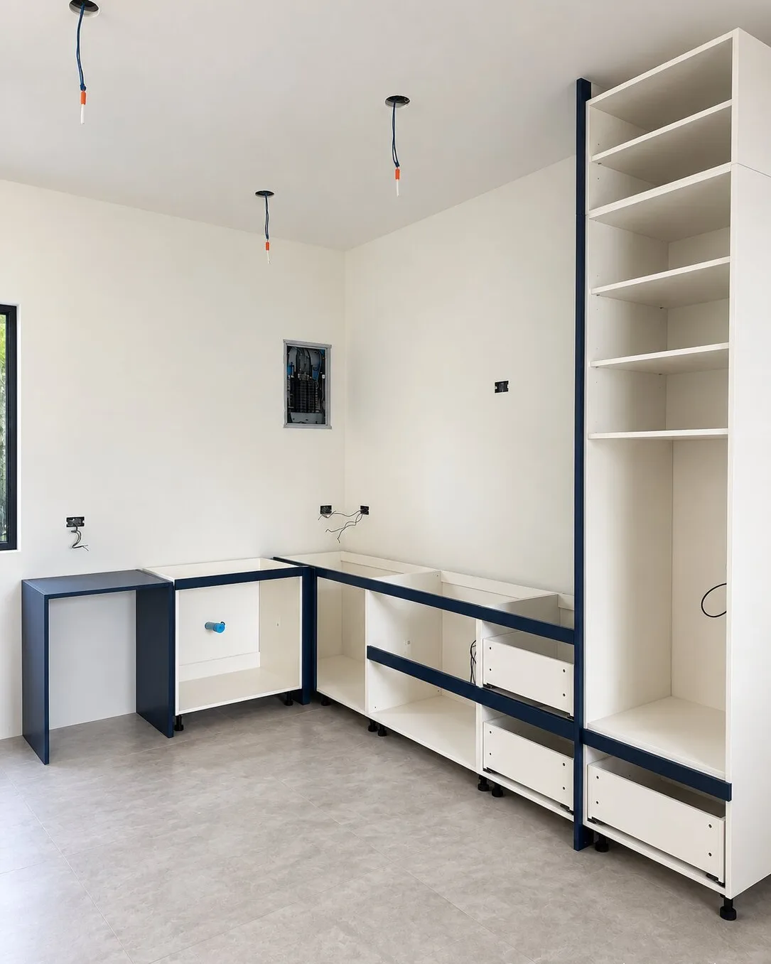 Navy and white fitted cabinet carcasses lined up against a wall mid-install