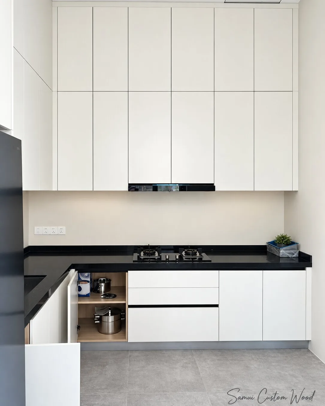 White fitted kitchen with black stone counter and wood-lined open cabinet