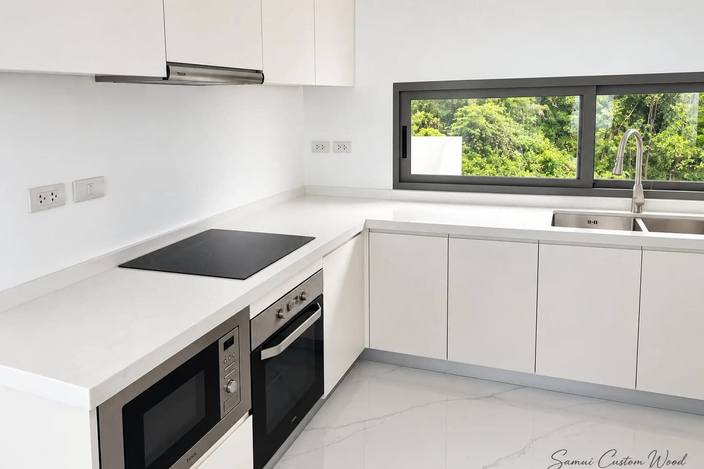 White L-shaped kitchen with built-in oven and a garden view window