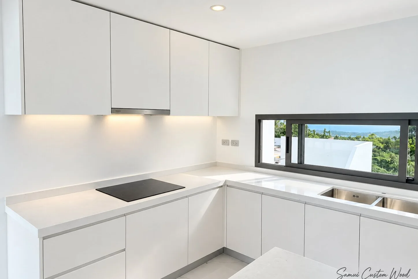 Minimal white kitchen with under-cabinet lighting and a hillside view window