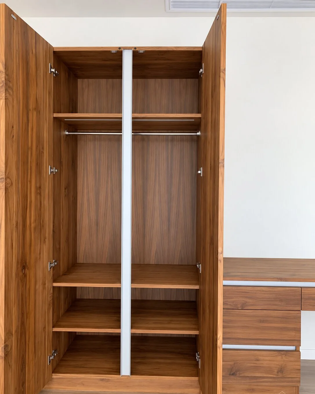 Open built-in wardrobe with fitted shelves, hanging rail and an integrated desk unit beside it