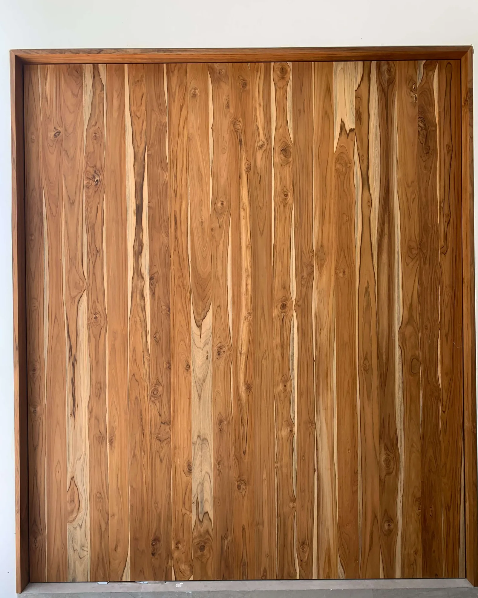 Full-height teak plank door panel hung in a teak frame