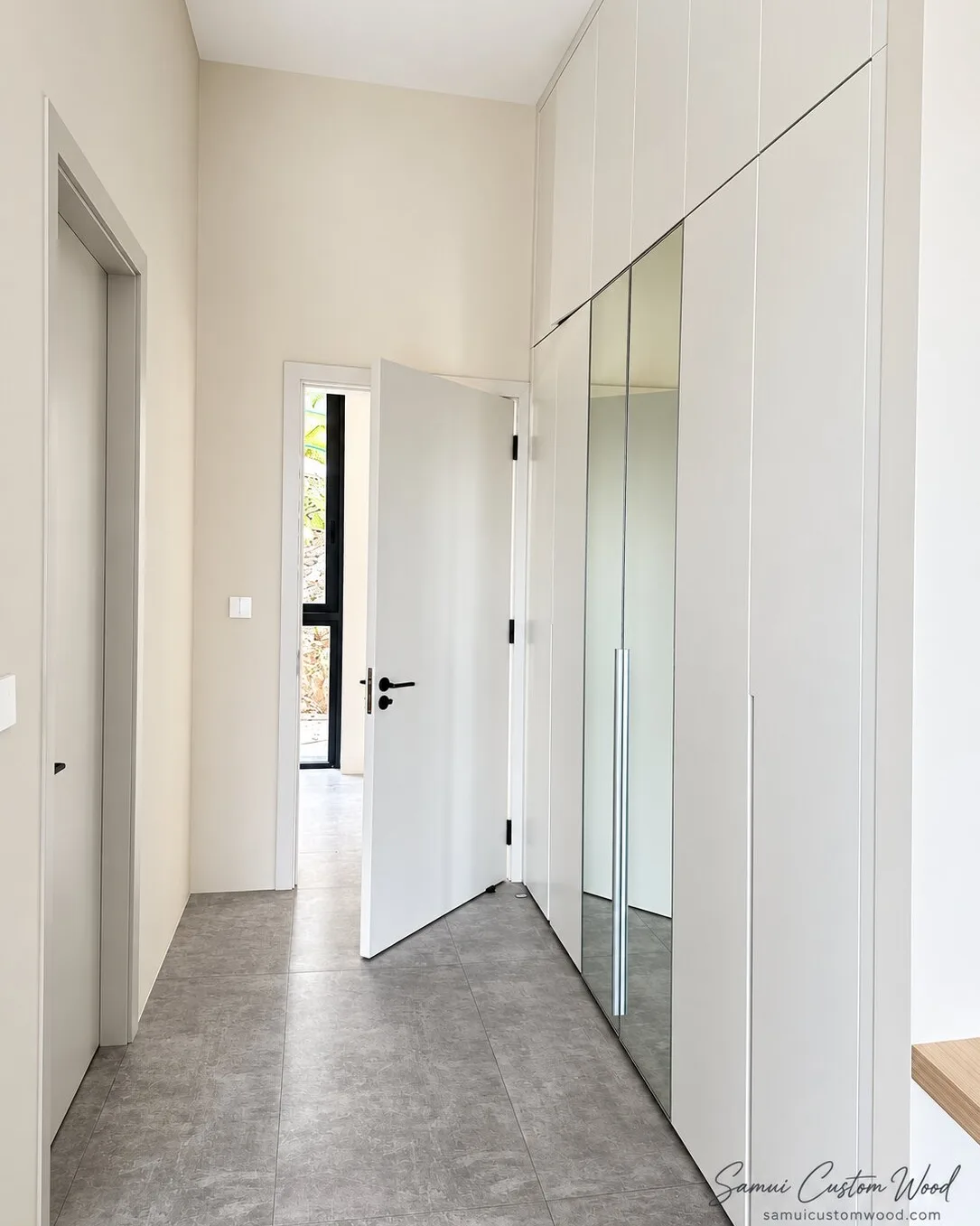 Tall white wardrobe doors and a mirror panel running down a corridor towards an open door