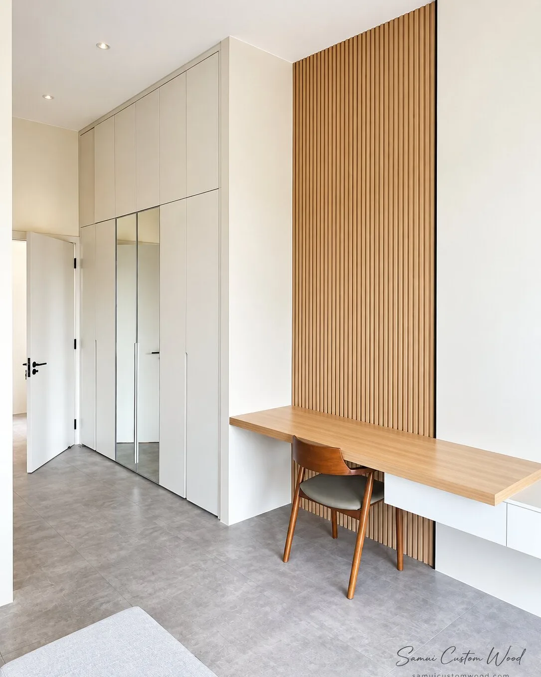 Vertical wood slat wall with a floating desk and chair beside full-height wardrobes