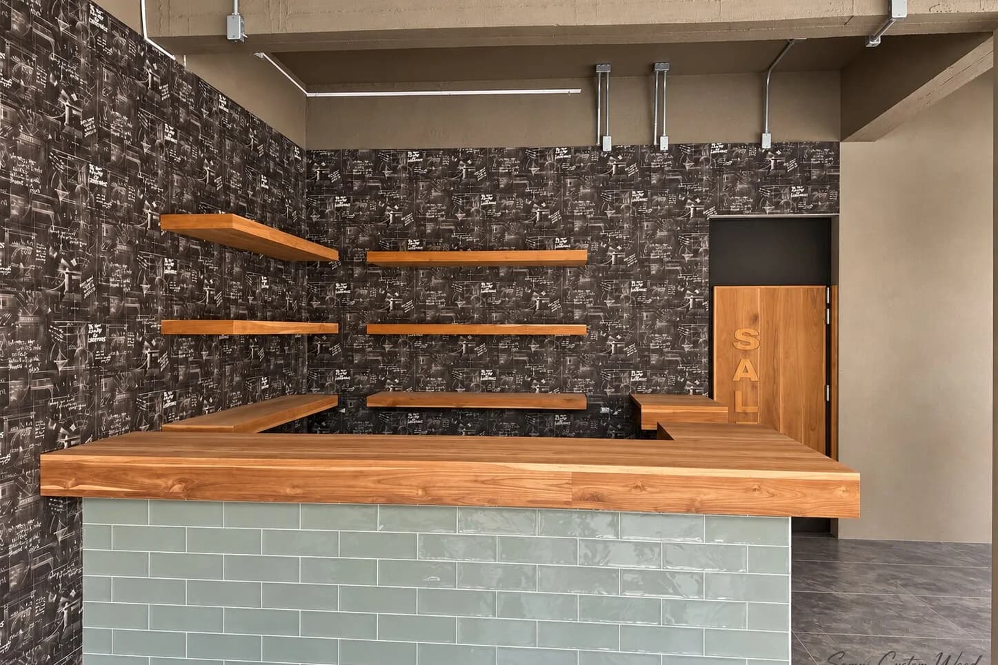 Teak bar counter and floating shelves in a shop interior with patterned walls