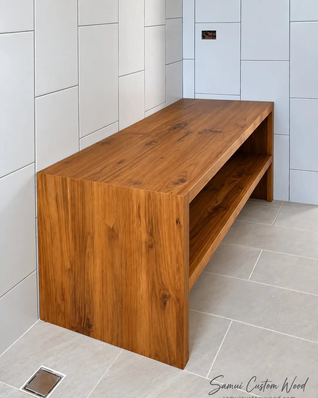 Solid teak bench with a low shelf in a tiled walk-in shower