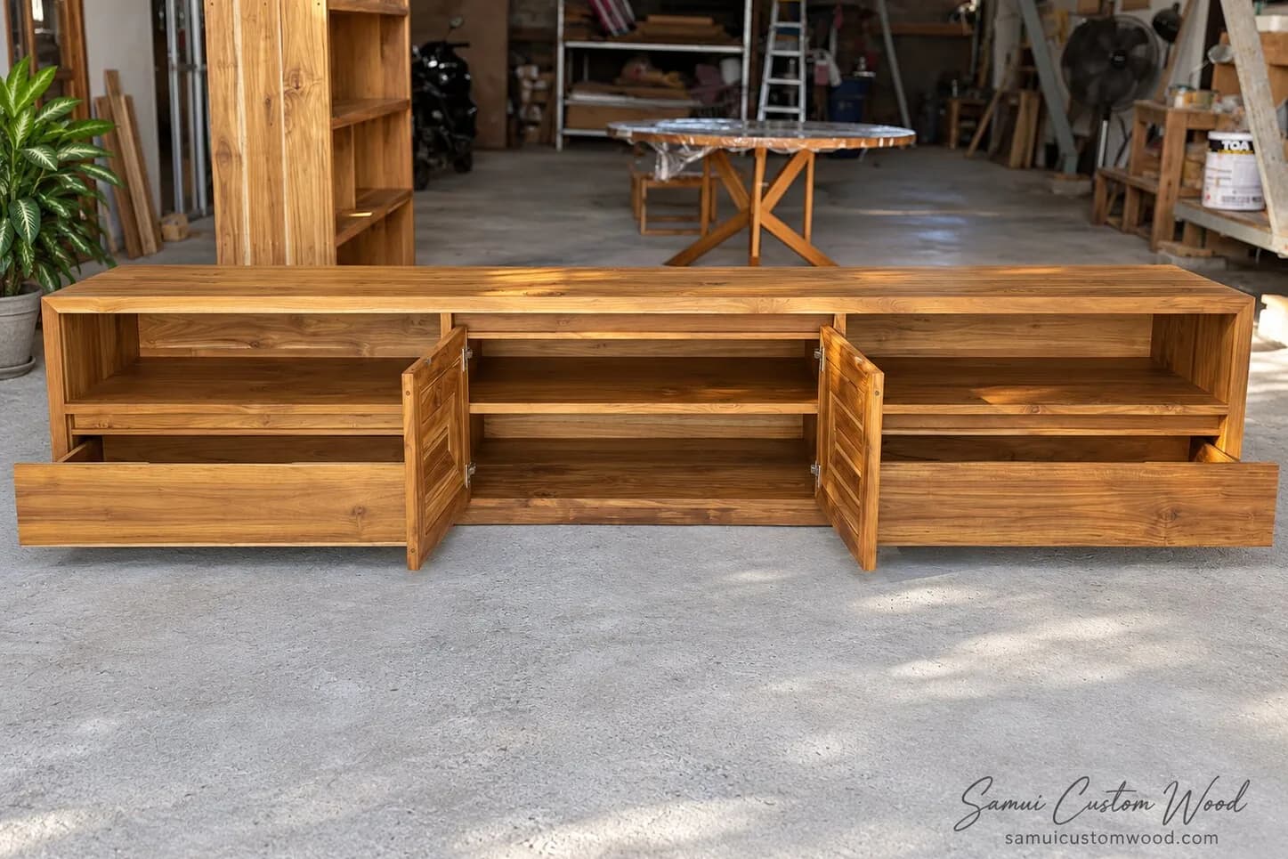 Long teak media console with drawers and louvred doors standing open
