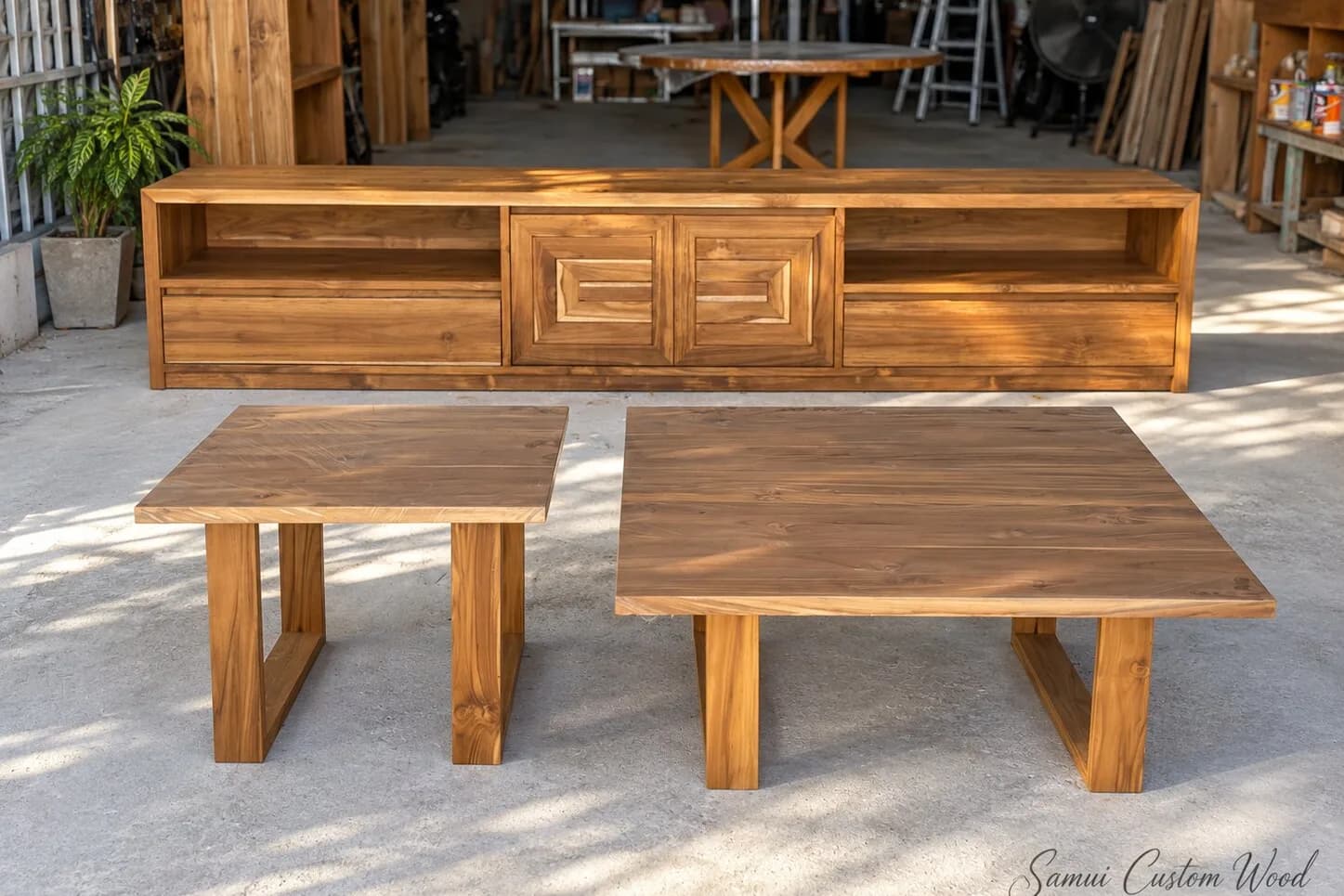 Teak media console and two square coffee tables lined up outside the workshop